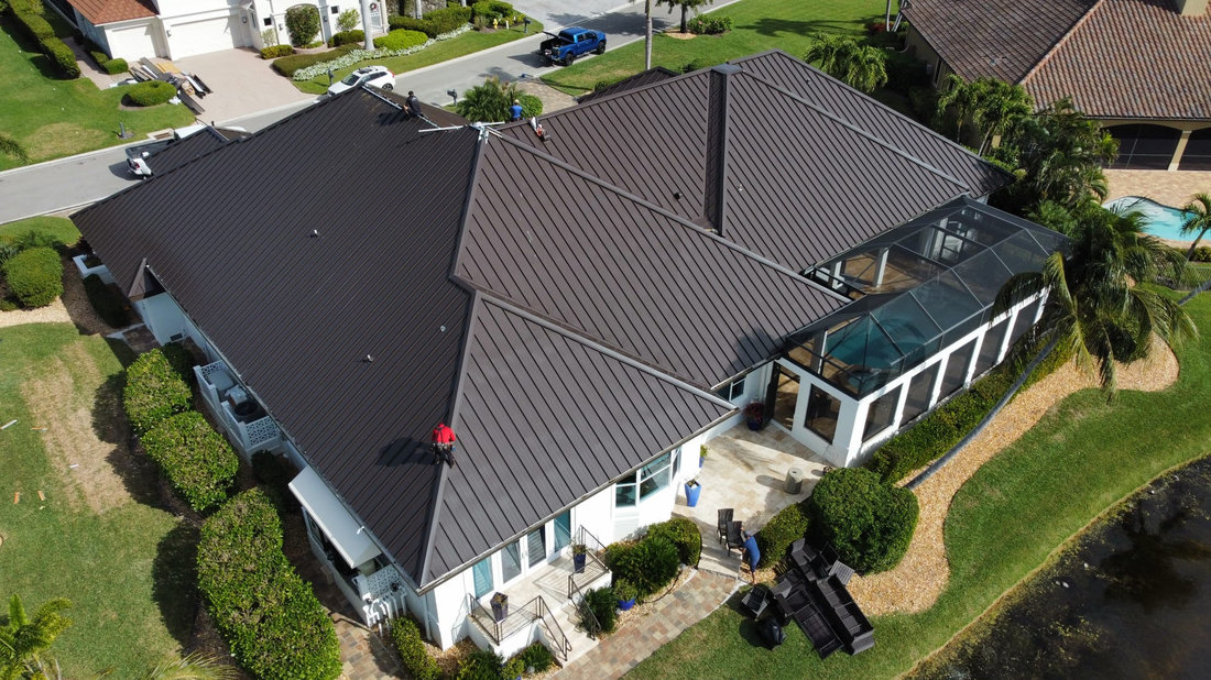 Workers carrying out roofing work on a dark metal roof
